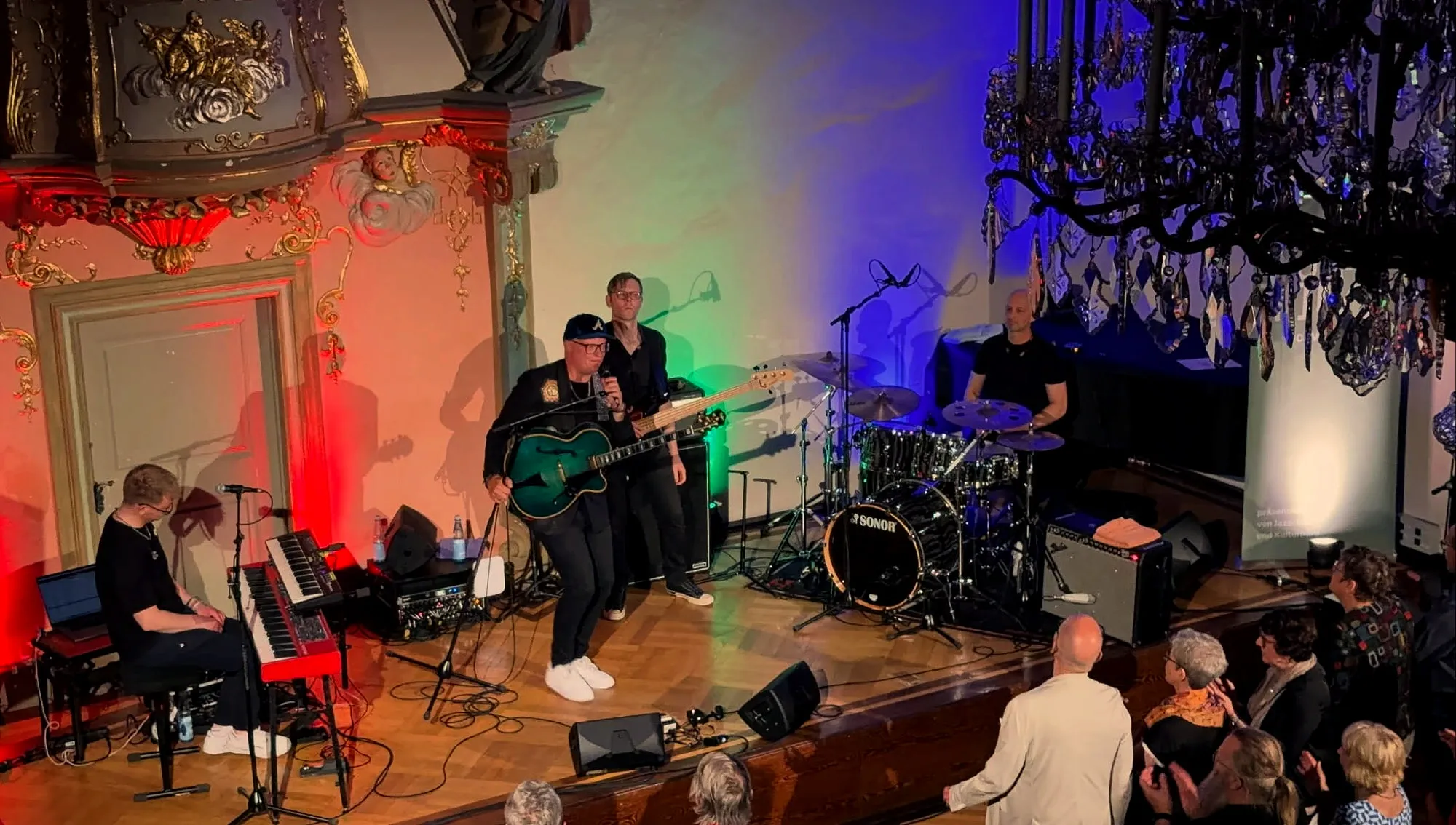 Jazzquartett auf der Bühne der Hospitalkirche Schwäbisch Hall, farbig ausgeleuchtet, mit Publikum in den vorderen Reihen